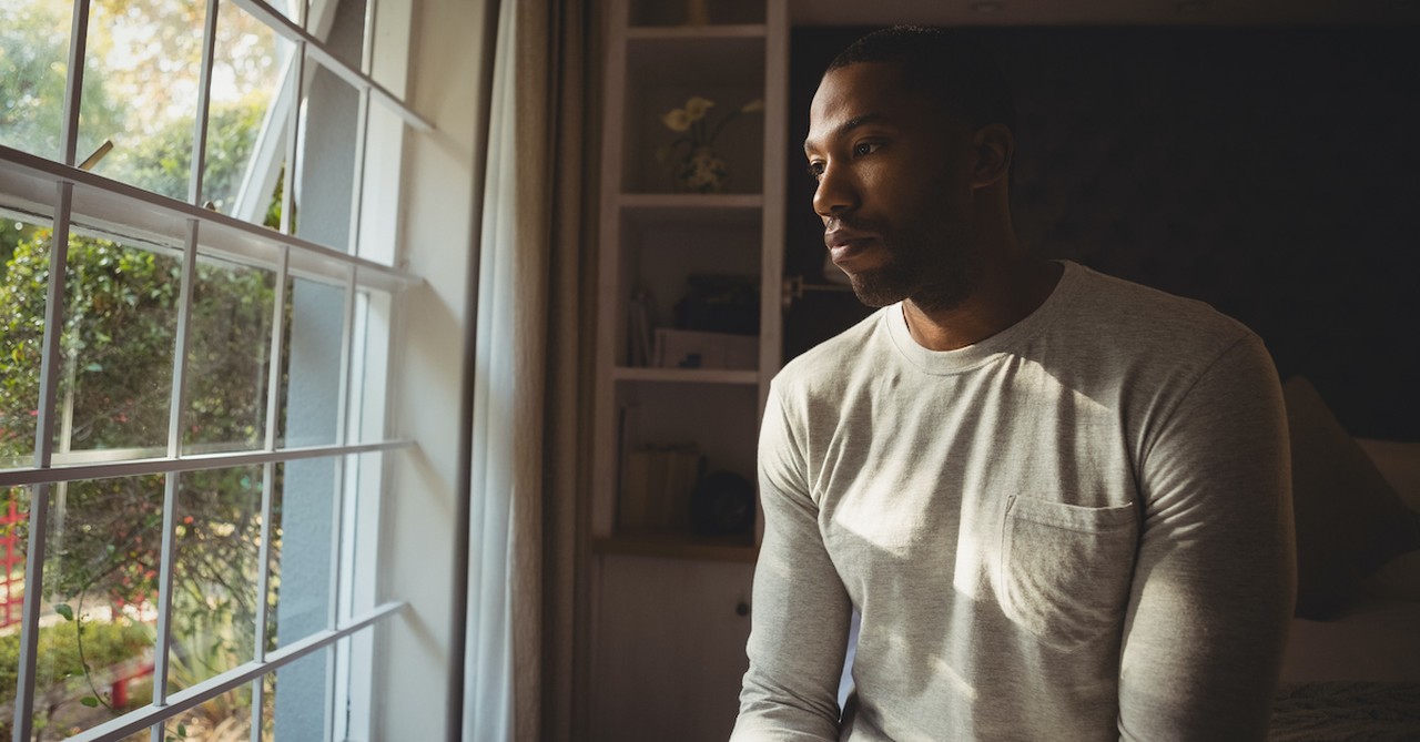 lonely man in isolation standing by window