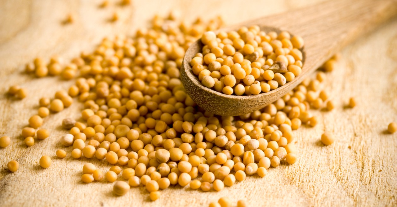ladle of mustard seeds spilling onto surface