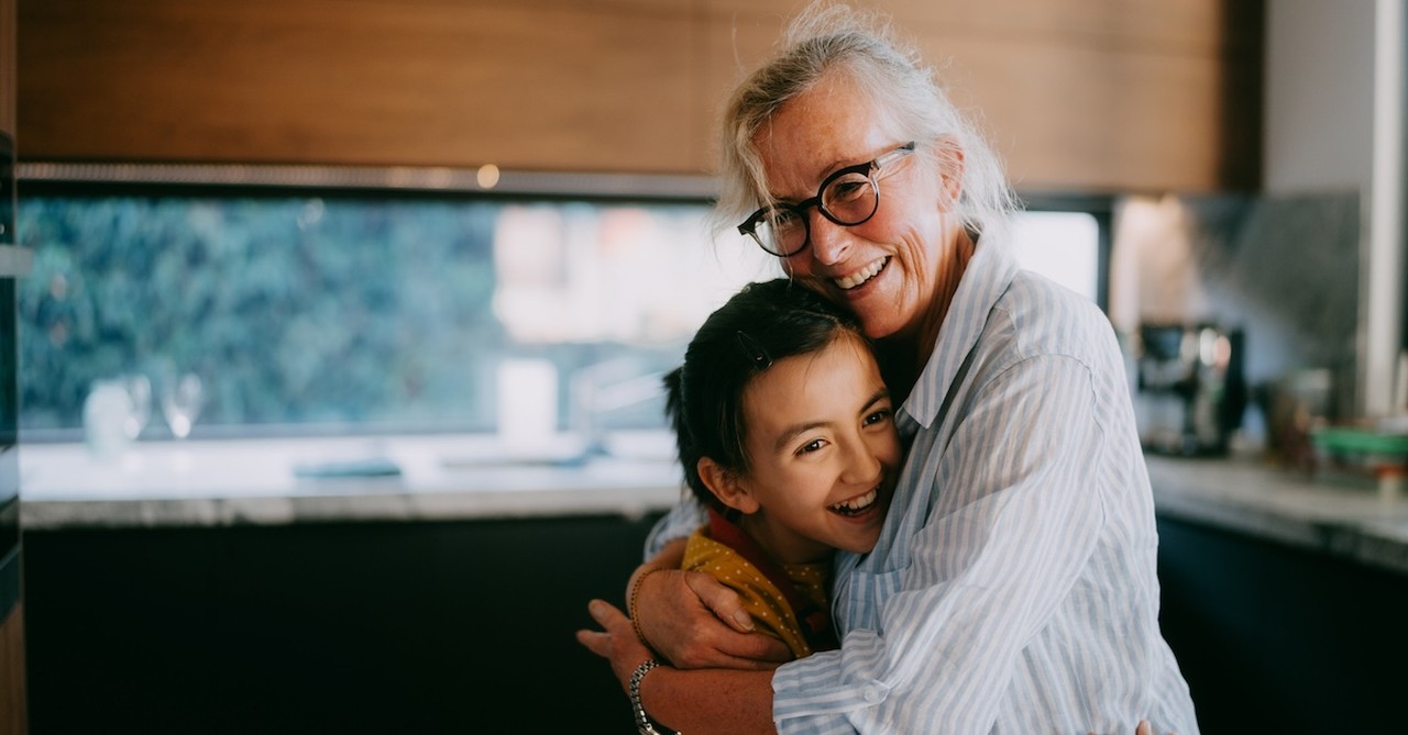 Grandma hugging granddaughter grandparent in kitchen