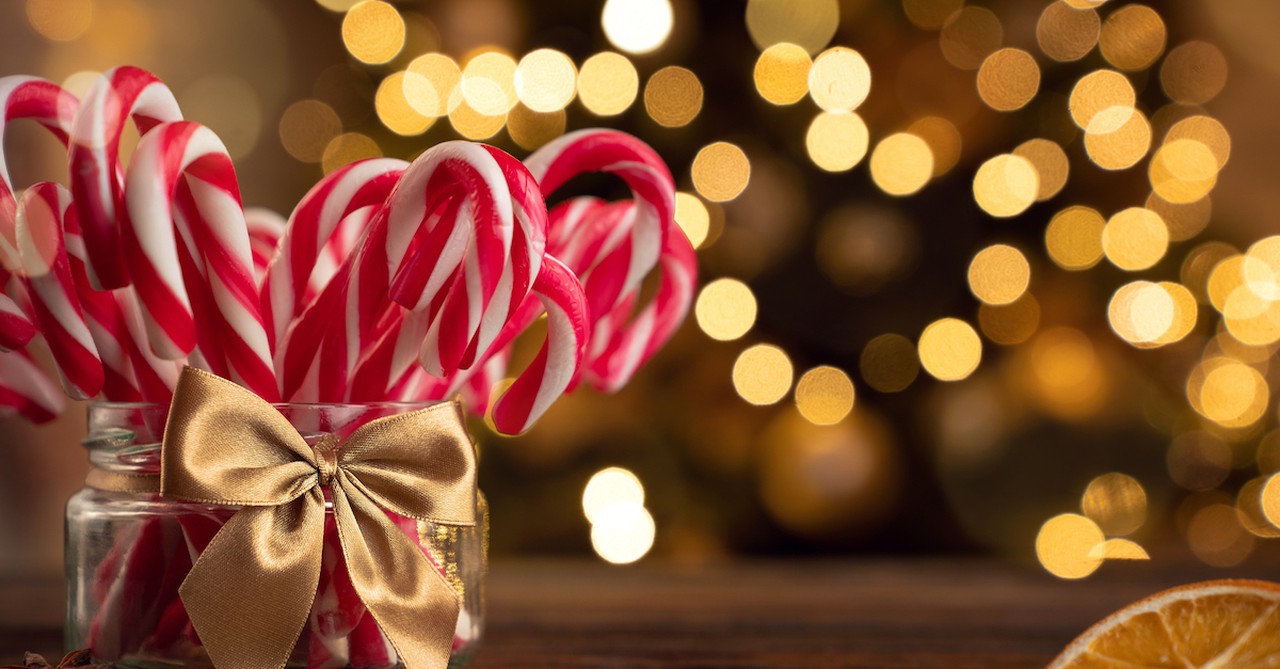 candy canes in a jar with christmas lights in background, origins of the candy cane